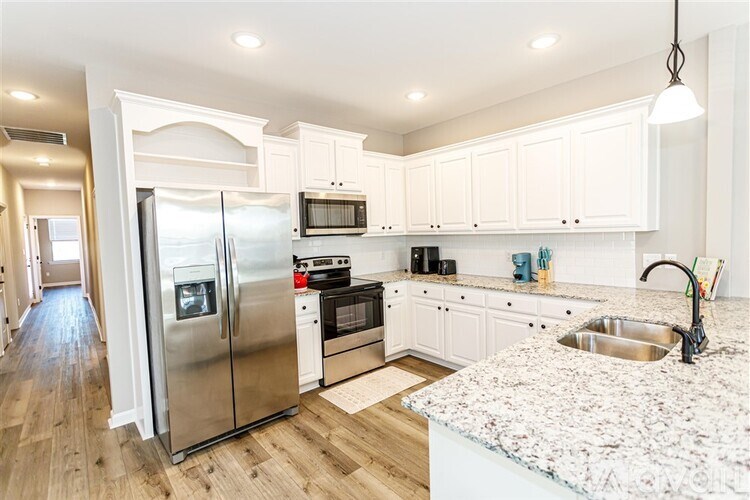 A kitchen with a granite counter top and stainless steel appliances.