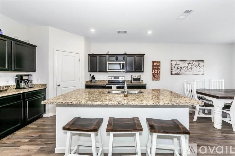 A kitchen with a granite countertop and white chairs.