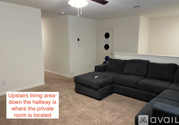 A living room with a black couch and a note on the wall.