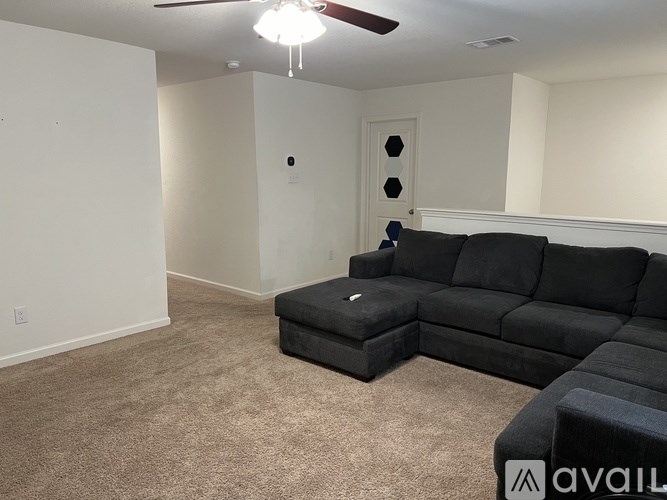 A living room with a black couch and ottoman.