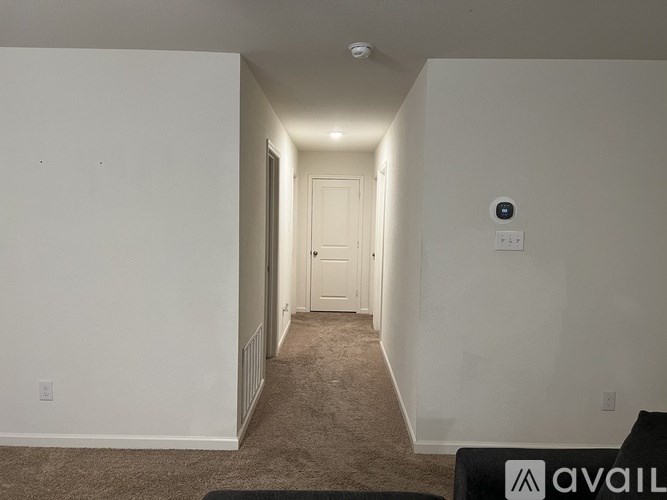 A hallway with a carpeted floor and a door at the end.