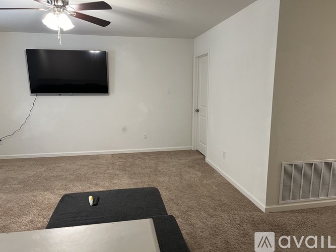 A room with a ceiling fan and a flat screen TV mounted on the wall.