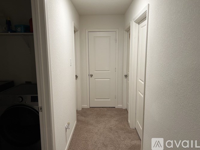 A hallway with a washing machine on the left and a door in the middle.