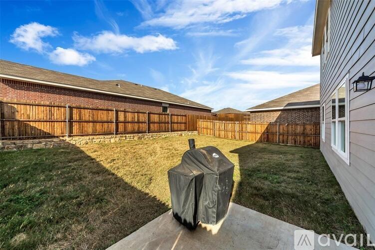 A backyard with a covered grill and wooden fence.