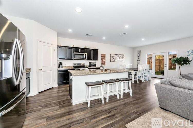 A modern kitchen with white cabinets and a wooden floor.