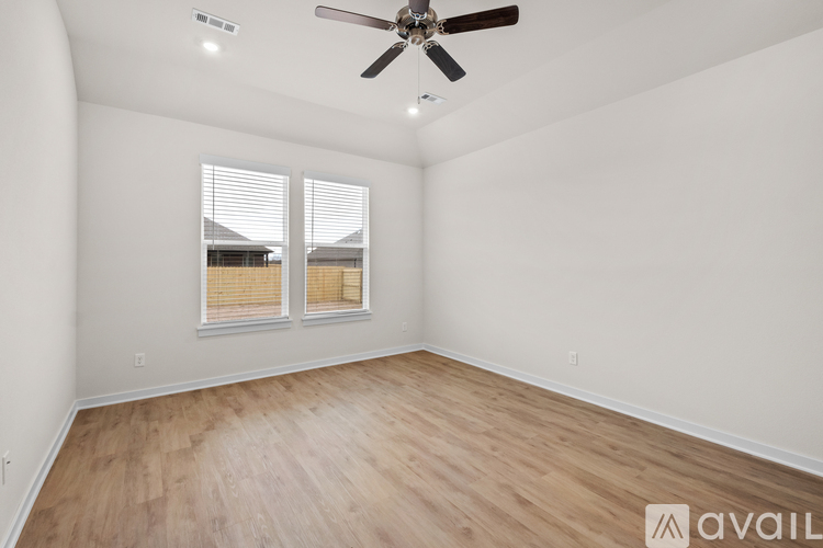 A room with a ceiling fan and wooden flooring.