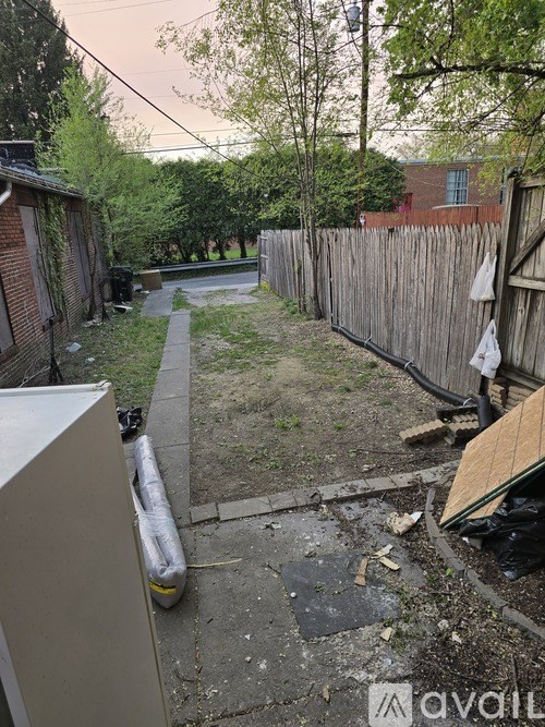 A backyard with a wooden fence and a trash can.