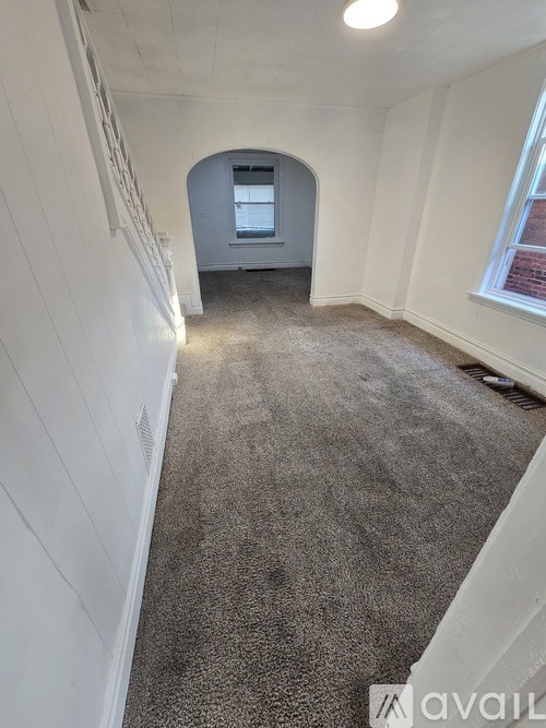 A long hallway with a carpeted floor and white walls.