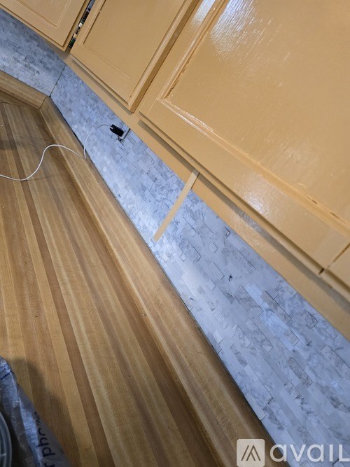 A white cord is plugged into a socket on a wooden floor.