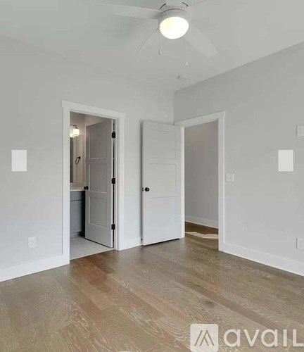 A room with a white door and a wooden floor.