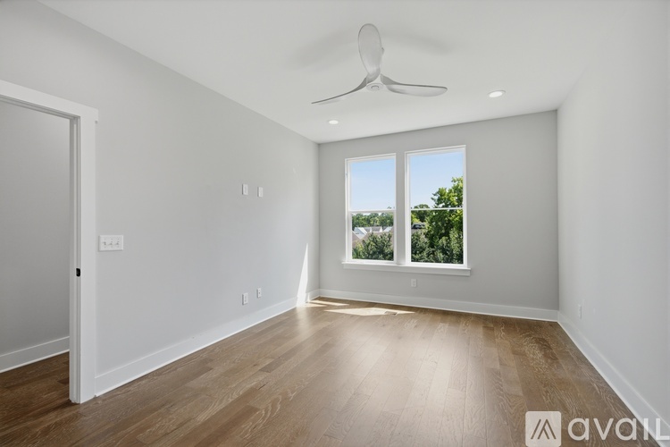 A spacious room with a ceiling fan and wooden flooring.