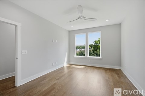 A spacious room with a ceiling fan and wooden flooring.