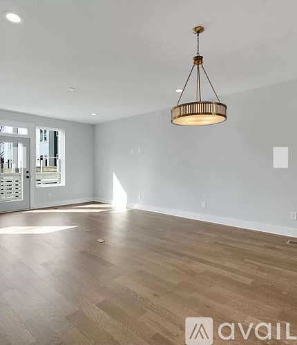 A room with wooden floors and a pendant light hanging from the ceiling.