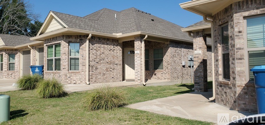 A house with a blue trash can in front of it.