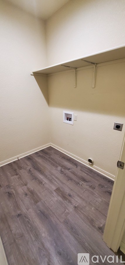 A room with a grey floor and a white wall with a shelf above it.