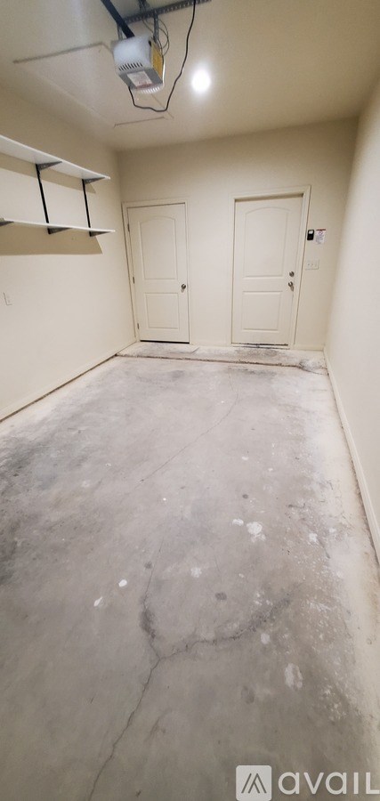 A room with two doors and a concrete floor.