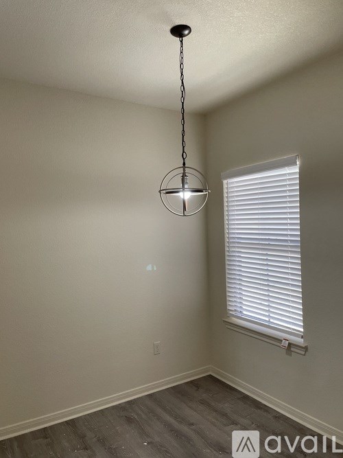 A room with a hanging light fixture and a window with blinds.