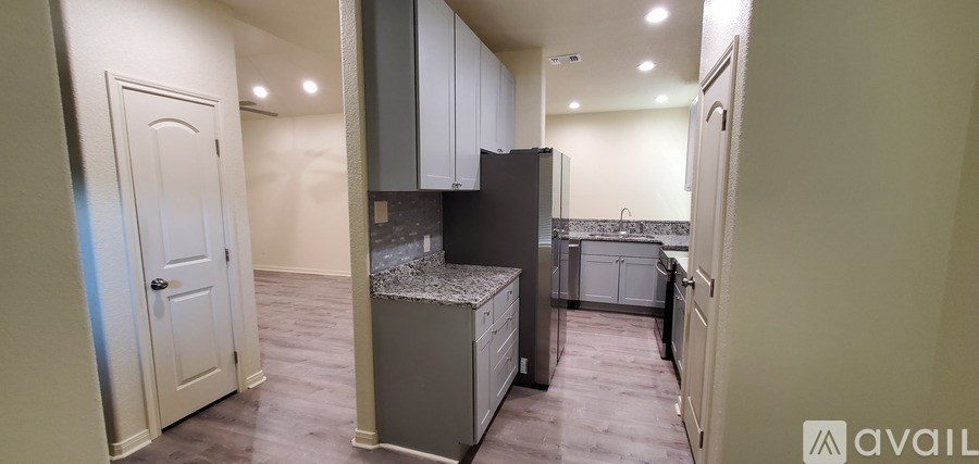 A kitchen area with a refrigerator, cabinets, and a countertop.