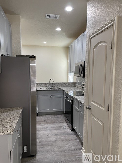 A kitchen with a refrigerator, microwave, and oven.