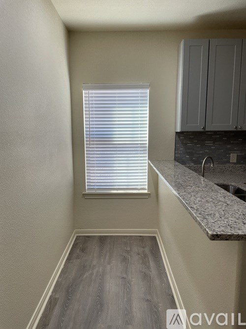 A kitchen area with a window covered in blinds.