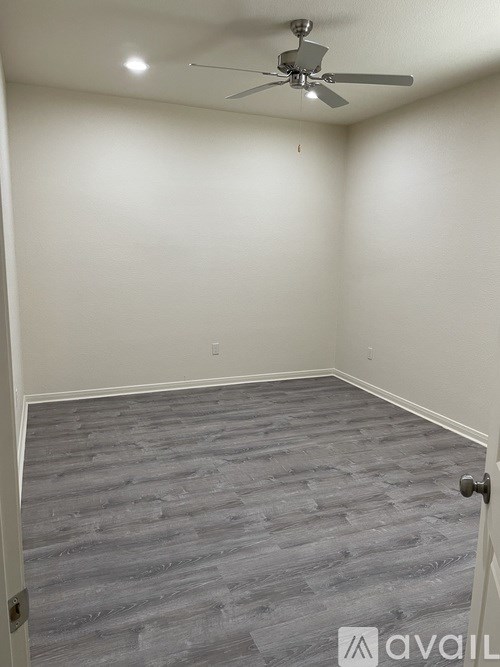 A room with a ceiling fan and grey flooring.