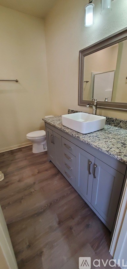 A bathroom with a wooden floor and a white sink.