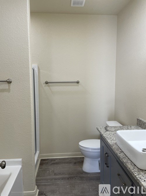 A small bathroom with a toilet, sink, and shower.