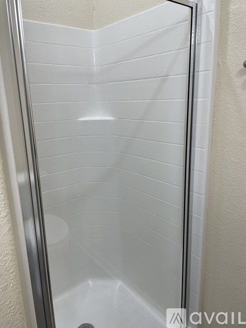 A shower stall with a glass door and white tiles.