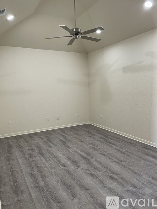 A room with a ceiling fan and grey flooring.
