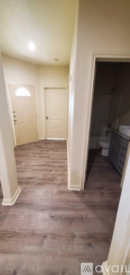 A hallway with two doors and a bathroom visible in the background.