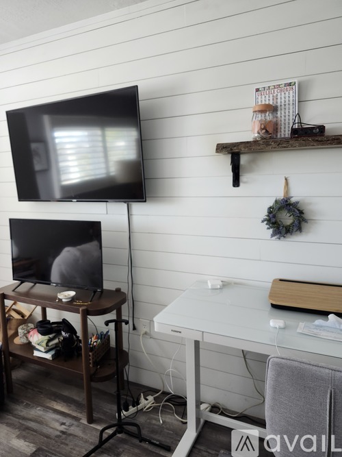 A black television is on a stand in front of a white wall.