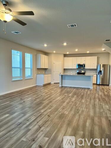 A spacious kitchen with wooden flooring and a ceiling fan.