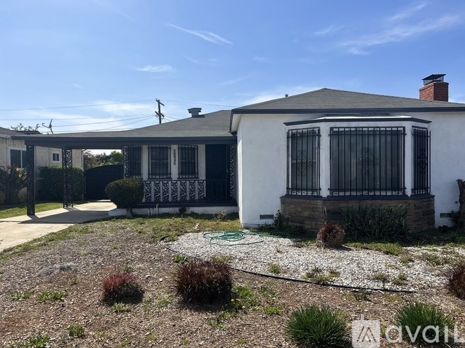 A white house with a black fence and a gravel driveway.