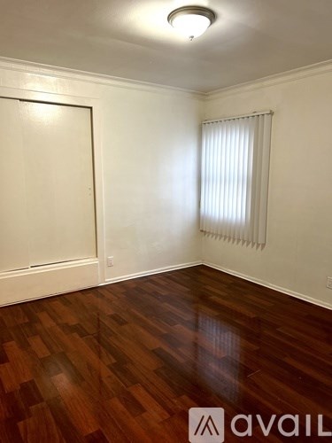 A room with wooden floors and a window with blinds.
