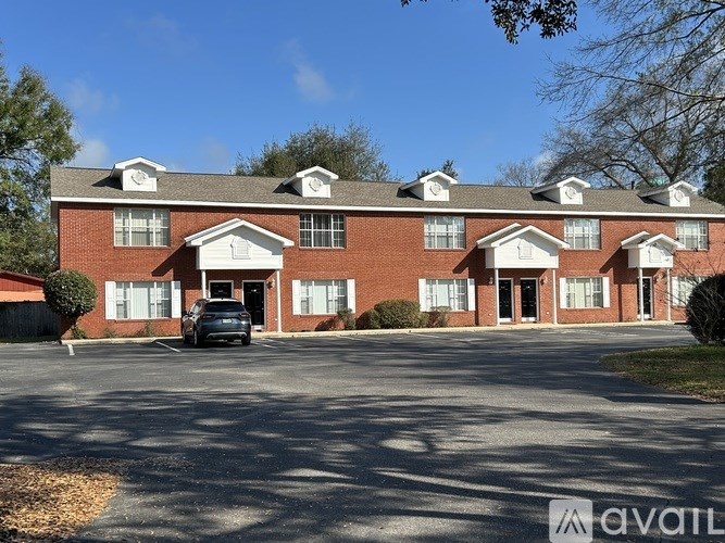 A large red brick building with a parking lot in front.