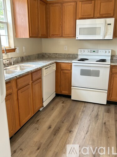 A kitchen with wooden cabinets and a white stove.