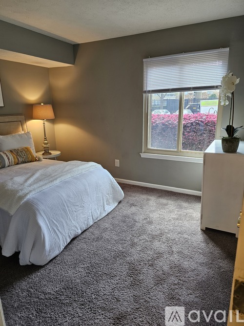 A bedroom with a bed, nightstand, and window.