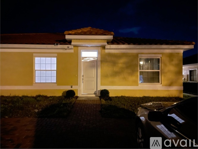 A house with a yellow front and a white door is shown at night.