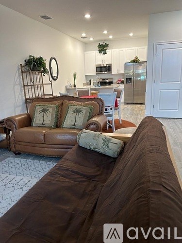 A living room with a brown couch and a kitchen in the background.