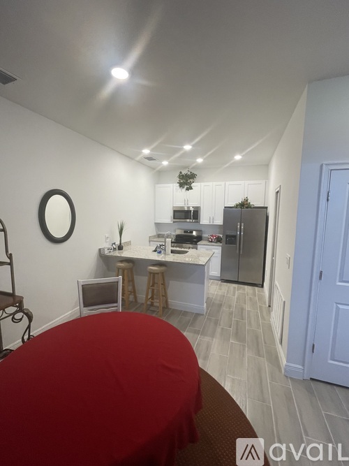 A kitchen area with a red table in the foreground.