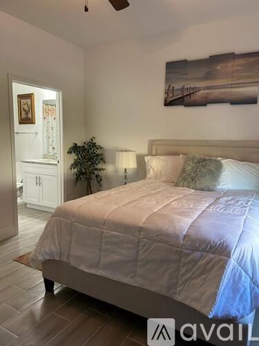 A bedroom with a large bed and a painting on the wall.