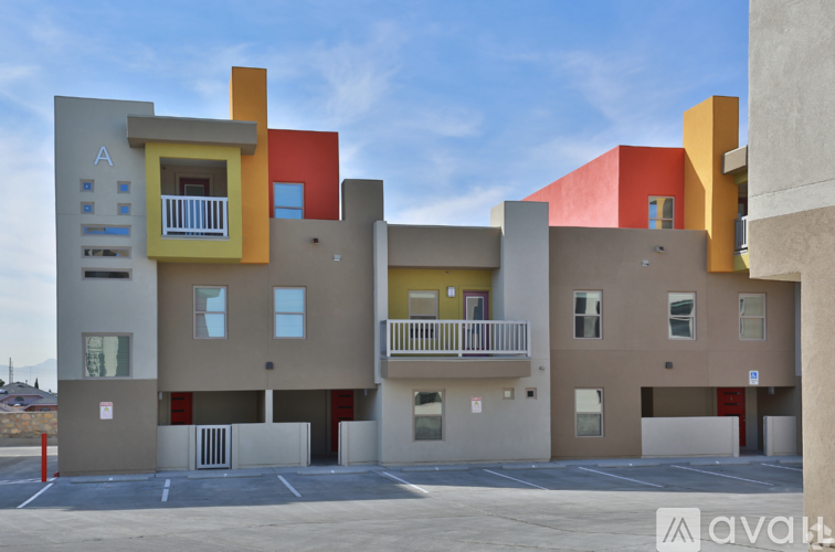 A modern building with a balcony and a parking lot in front.