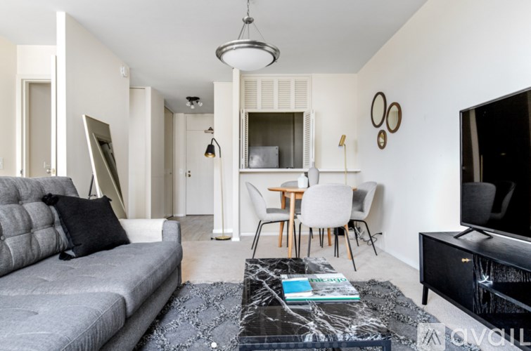 A living room with a grey sofa, a black coffee table, and a television.