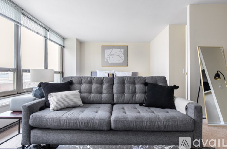 A grey couch with pillows sits in a room with a large window.
