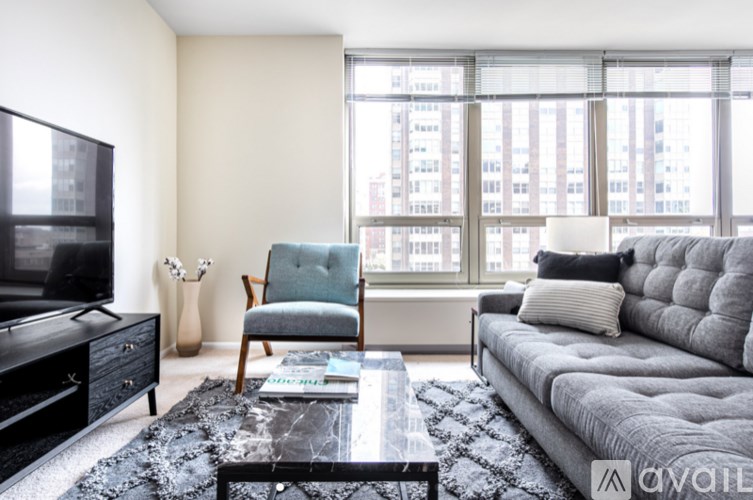 A living room with a grey couch, a black coffee table, and a black television.