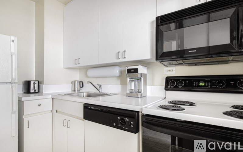 A white kitchen with black appliances and a white fridge.
