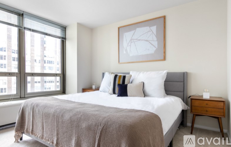 A bedroom with a large bed and a window overlooking a city.