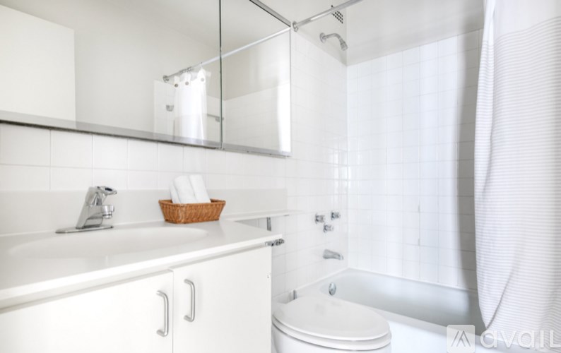 A white bathroom with a toilet, sink, and shower.