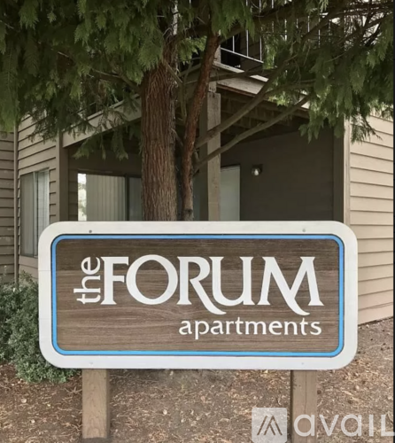 A sign for "The Forum Apartments" is displayed in front of a building.