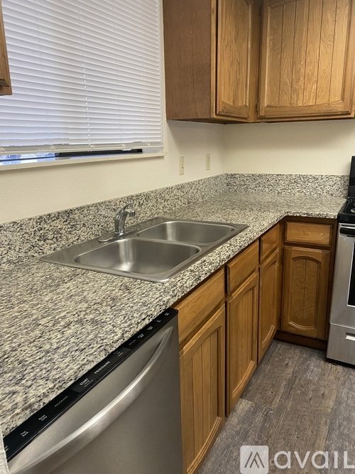 A kitchen with a granite countertop and wooden cabinets.